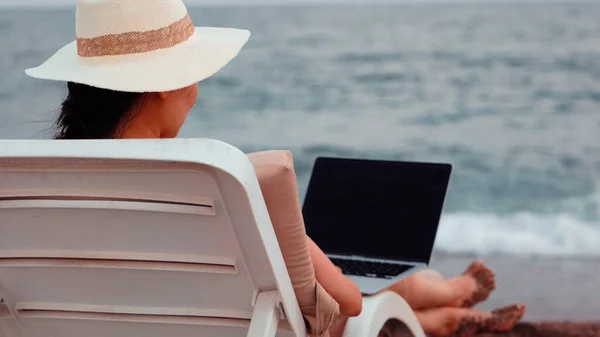 Freelancer woman working on laptop near the sea. Remote work concept. work on vacation. High quality 4k footage