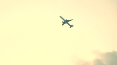 Airplane flies into clouds on gold sky. High quality 4k footage
