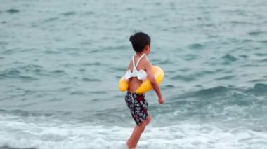 Happy Little child with swimming circle swims on the sea. Boy has fun on waves. High quality 4k footage