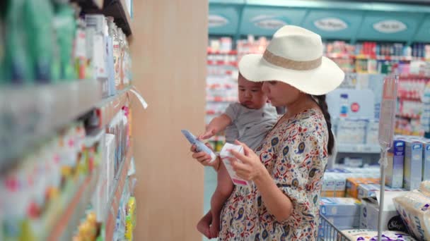 Young Modern Single Mother Choosing Baby Cream Supermarket High Quality — Vídeo de Stock