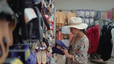 Woman looking for a flip-flops in supermarket. High quality 4k footage
