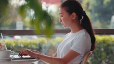 Young freelancer woman typing on laptop sitting at cafe. Remote work concept. High quality 4k footage