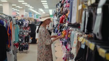 Woman looking for a flip-flops in supermarket. High quality 4k footage