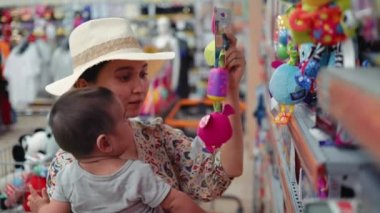 Young modern single mother choosing toys in supermarket. High quality 4k footage