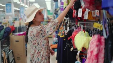 Woman looking for a swimsuit in supermarket. High quality 4k footage