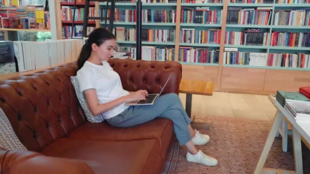 Concentrated Young Woman Remote Worker Using Laptop Sitting Couch Library — Vídeos de Stock