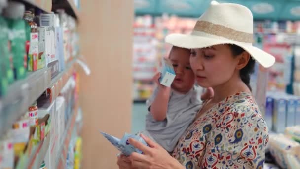 Young Modern Single Mother Choosing Baby Cream Supermarket High Quality — Vídeos de Stock