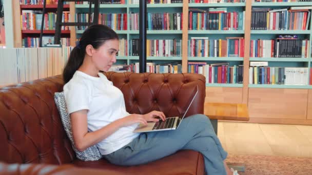 Serious Young Woman Remote Worker Using Laptop Sitting Couch Library — Vídeos de Stock