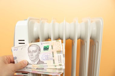 heating radiator, money. Ukrainian hryvnia on the background of the radiator.