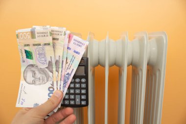 heating radiator, money. Ukrainian hryvnia on the background of the radiator. calculator
