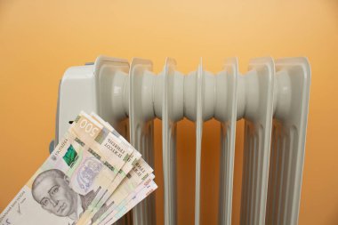 heating radiator, money. Ukrainian hryvnia on the background of the radiator.