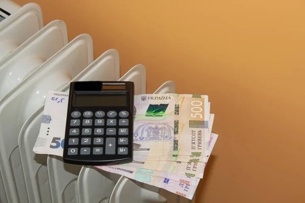 heating radiator, money. Ukrainian hryvnia on the background of the radiator. calculator