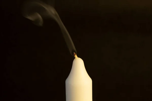 a white candle on a black background, an extinguished candle.