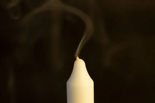a white candle on a black background, an extinguished candle.