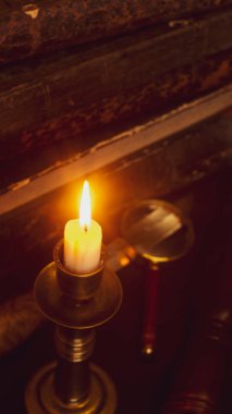 Masadaki eski kitaplar, mum ışığında okumak, büyüteç.