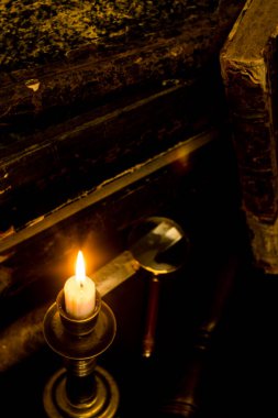 Masadaki eski kitaplar, mum ışığında okumak, büyüteç.