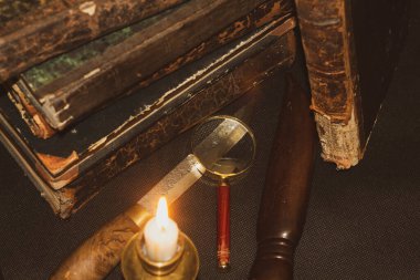 Masadaki eski kitaplar, mum ışığında okumak, büyüteç.