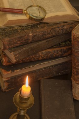 Masadaki eski kitaplar, mum ışığında okumak, büyüteç.