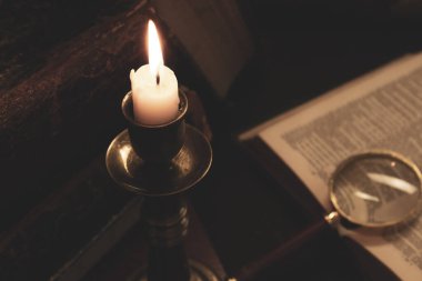 Masadaki eski kitaplar, mum ışığında okumak, büyüteç.