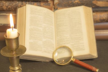 Masadaki eski kitaplar, mum ışığında okumak, büyüteç.