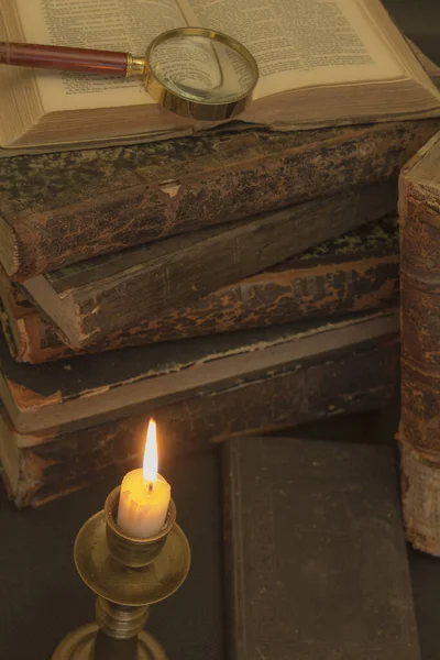 Masadaki eski kitaplar, mum ışığında okumak, büyüteç.