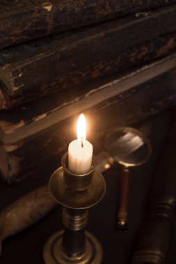 Masadaki eski kitaplar, mum ışığında okumak, büyüteç.