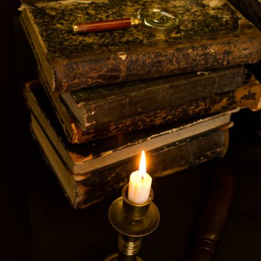 Masadaki eski kitaplar, mum ışığında okumak, büyüteç.