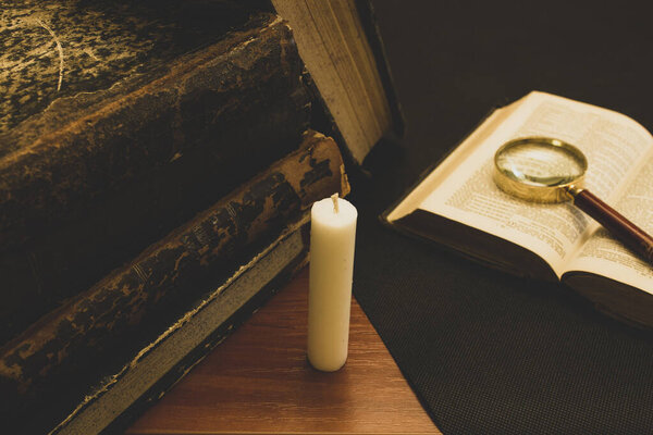 old books on the table, reading by candlelight, magnifier