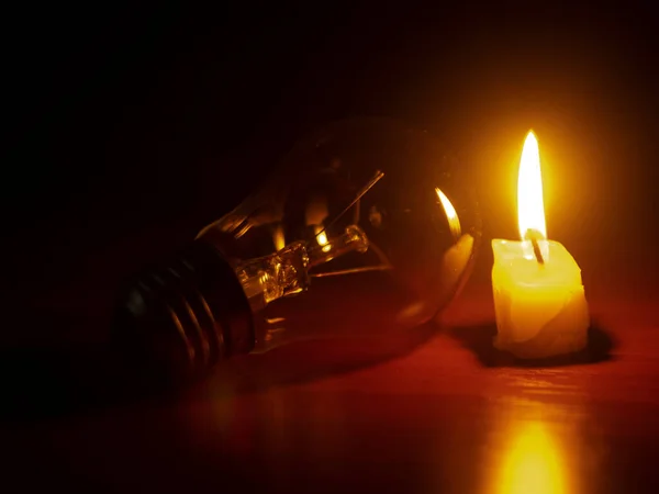 light bulb and candle on black background