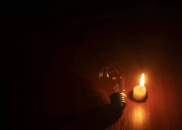 light bulb and candle on black background