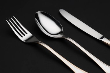 Siyah arkaplanda parlak gümüş çatal bıçak takımı