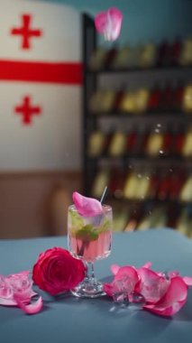 Masaya düşen pembe kokteyl ya da limonata, cam ve gül yaprakları.