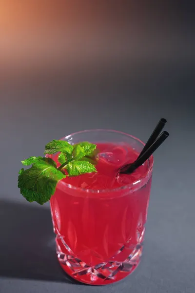 Nahaufnahme eines roten Erdbeer-Cocktailgetränks mit Minze im Glas auf grauem Hintergrund — Stockfoto
