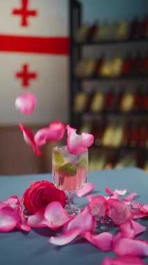 Masaya düşen pembe kokteyl ya da limonata, cam ve gül yaprakları.