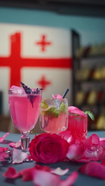 Rosa Cocktail und Limonadengetränk im Glas und Rosenblätter fallen auf den Tisch — Stockvideo