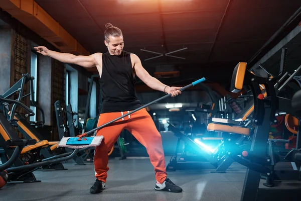 Atractivo atleta masculino limpiador divertirse y bailar y hacer limpieza en el gimnasio —  Fotos de Stock