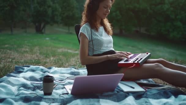 Счастливая девушка-музыкант, играющая синтезатор на клавиатуре и композицию под открытым небом — стоковое видео