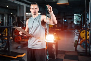 Spor salonunda mezurası olan yakışıklı bir özel antrenör beslenme uzmanı.