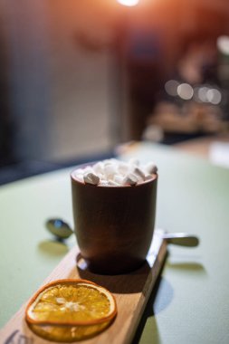 Bir fincan sıcak çikolatalı kakao ve kafedeki ahşap tabakta tatlı marşmelov.