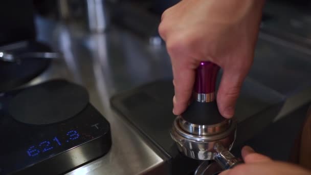 Бариста делает эспрессо и отжимает измельченную кофейную фасоль в тампере — стоковое видео