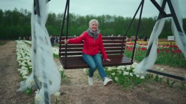 Olgun yaşlı kadın parkta dinleniyor ve sallanıyor.