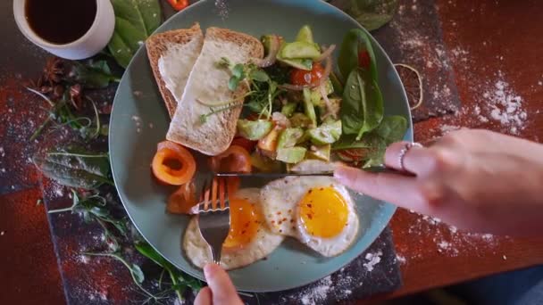 Person äter frukost med stekta ägg, bröd, avokado, röd fisk lax och kaffe — Stockvideo