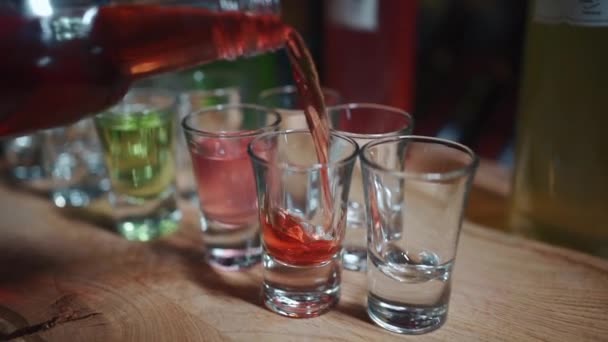 Bartender menuangkan minuman beralkohol berwarna-warni, vermouth atau minuman berumbai dalam gelas — Stok Video