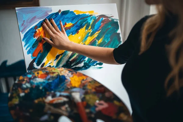 Fêmea criativa com quadro de pintura de paleta por dedos em tela com cavalete — Fotografia de Stock