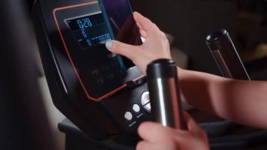 Kişi eliptik makinenin konsol panelinin rafına telefon koydu