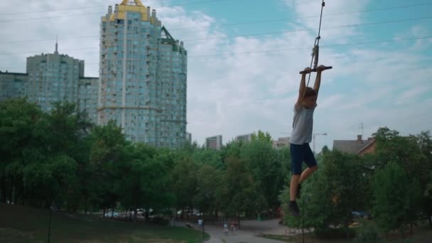 Actieve kid jongen swing op zelfgemaakte bungee op boom of plezier hebben in de stad park outdoor — Stockvideo