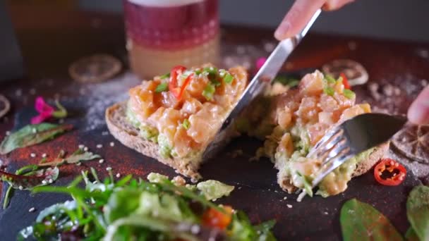 Persona come sándwich fresco con aguacate, salmón rojo pescado, rúcula, tomate, ensalada — Vídeo de stock