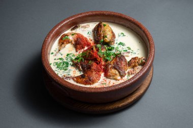 Gürcü chkmeruli krema soslu chiken eti koyu arkaplanda killi kasede