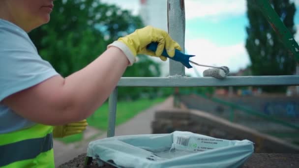 Dobrovolný pracovník malba štětcem nebo válečkem a renovovat zábradlí nebo plot — Stock video