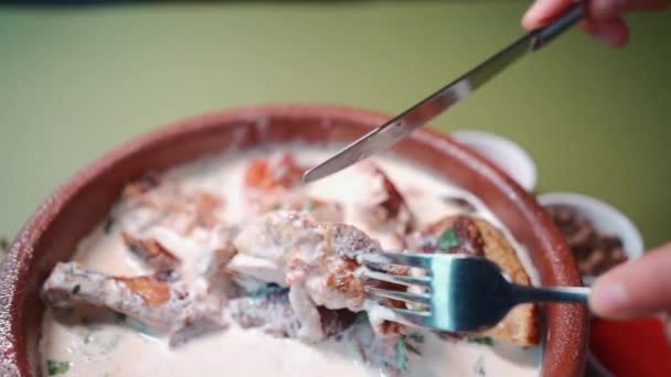 Jíst georgian chkmeruli s vidličkou nebo kuřecím masem v smetanové omáčce v hliněné misce — Stock video